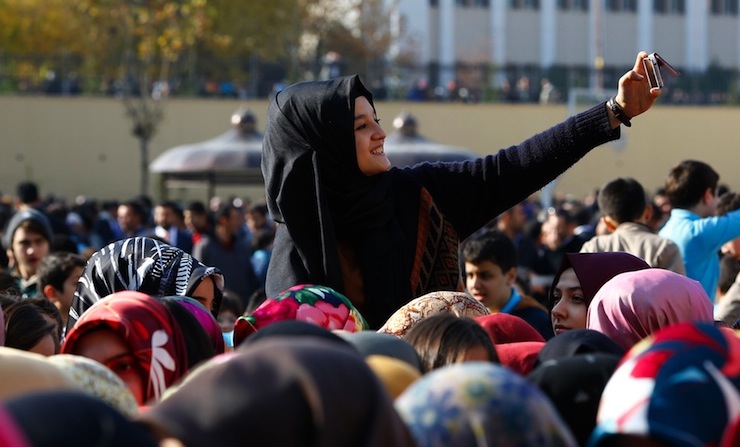 A student of Tevfik Ileri Imam Hatip School takes a "selfie" as she joins others in waiting for the arrival of President Tayyip Erdogan for the opening ceremony in Ankara