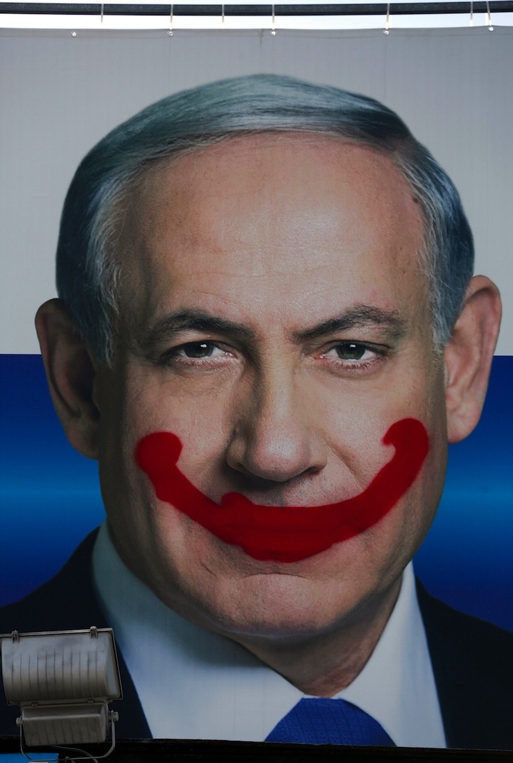A defaced Likud party campaign billboard depicting Israeli Prime Minister Benjamin Netanyahu is seen in Tel Aviv