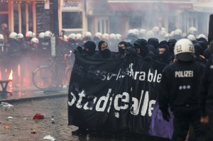 Protesters hold up a banner during clashes in front of the 'Rote Flora' cultural centre during a demonstration in Hamburg