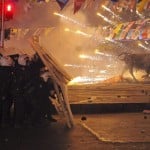 Riot policemen shield themselves as fireworks thrown by protesters explode next to the statue of a bull, during an anti-government protest in Kadikoy
