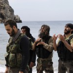 Rebel fighters pray at the beach of al-Samra in Latakia province near the town of Kasab