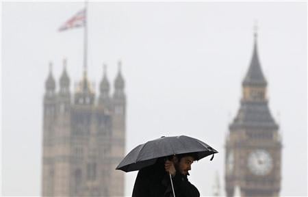 A pedestrian carries an umbrella as he walks across Waterloo Bridge in London