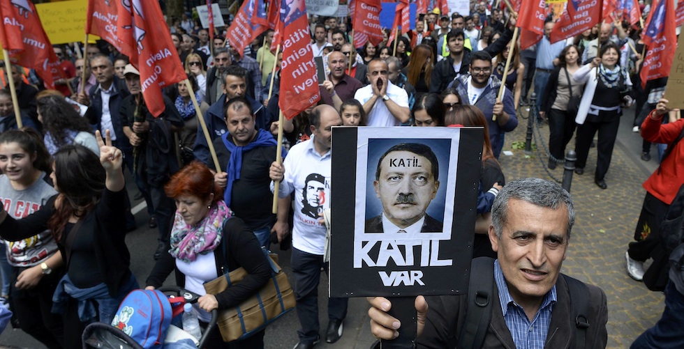 Protester carries a poster depicting Turkish Prime Minister Erdogan with a text reading "Murderer" during a rally against Erdogan's visit in Cologne