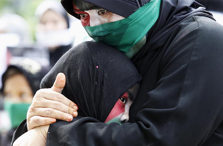 Filipino Muslim woman cries as she embraces child during rally held by Anak Mindanao Party List group outside Israeli embassy in Taguig
