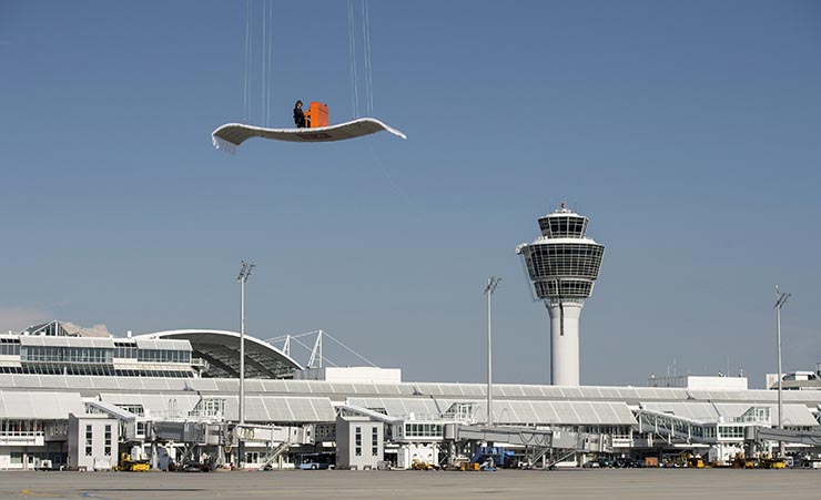 German pianist Stefan Aaron plays an orange piano on a "flying carpet" platform suspended from a helicopter, over the Munich airport