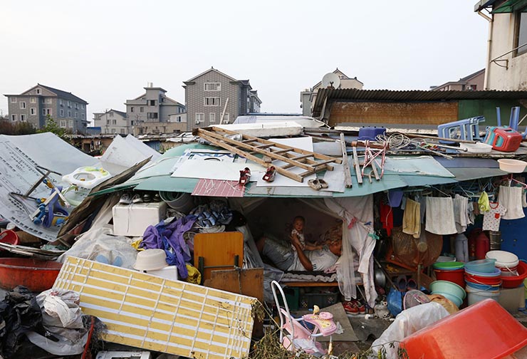 A migrant worker plays with his daughter at their makeshift home on the outskirts of Hangzhou