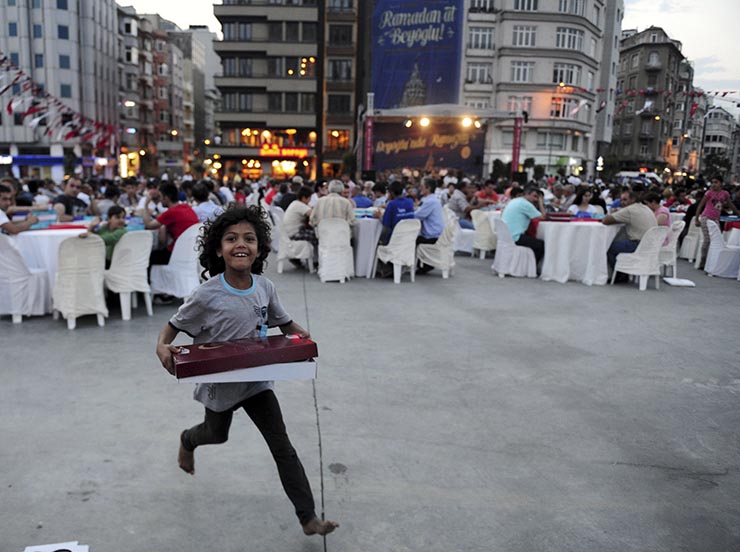 A Syrian refugee girl runs as she receives a pack of food at an iftar event during Ramadan in Istanbul