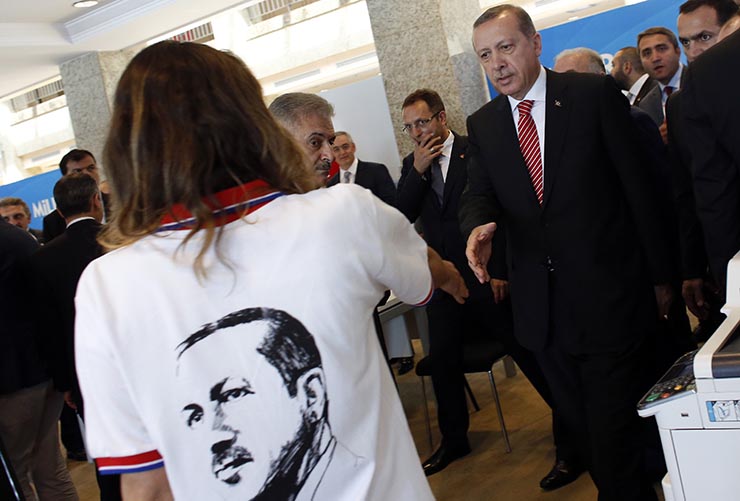 Turkey's Prime Minister and presidential candidate Erdogan shakes hands with a staff member as he visits his election coordination center in Istanbul