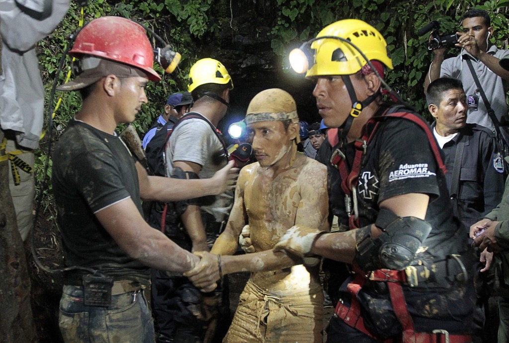Miners and rescue workers hold a miner covered in mud after he was rescued from a gold mine blocked by a landslide in Bonanzas town