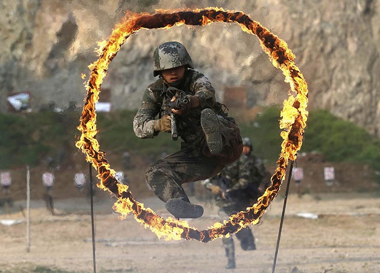 A PLA coastal defence force member jumps through a burning obstacle during a drill to mark the 87th Army Day at a military base in Qingdao