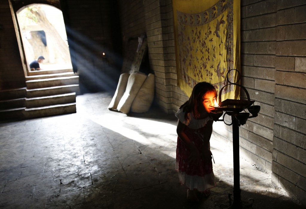 A displaced girl from the minority Yazidi sect, who fled violence in the Iraqi town of Sinjar, worships at their main holy temple Lalish in Shikhan
