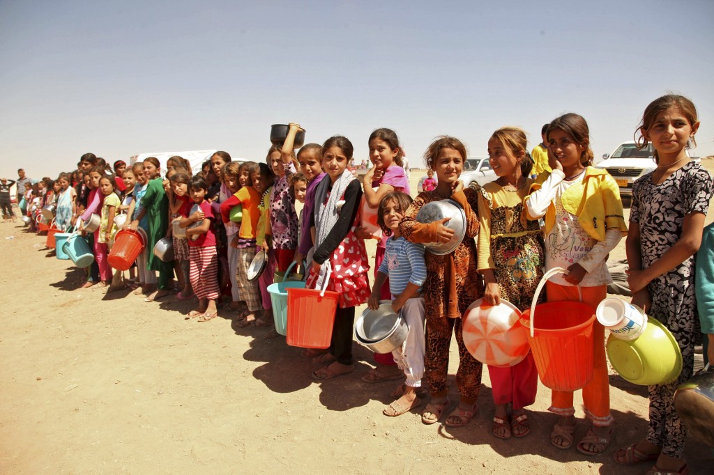 Displaced people from the minority Yazidi sect line up to receive food at the khanki camp on the outskirts of Dohuk