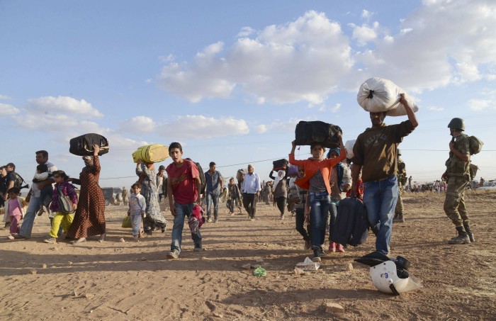 Syrian Kurds walk with their belongings after crossing into Turkey at the Turkish-Syrian border, near the southeastern town of Suruc in Sanliurfa province