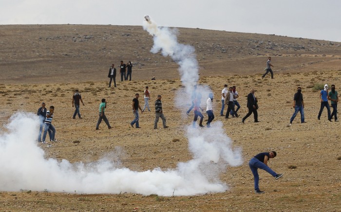 A Turkish Kurdish protestor throws back a tear gas capsule at riot police near the Turkish-Syrian border in the southeastern town of Suruc in Sanliurfa province
