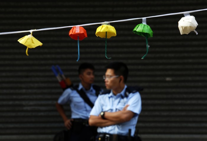 Policemen stand guard on a blocked road behind an installation of paper umbrellas, considered a symbol of the Occupy Central movement, at the Causeway Bay shopping district in Hong Kong