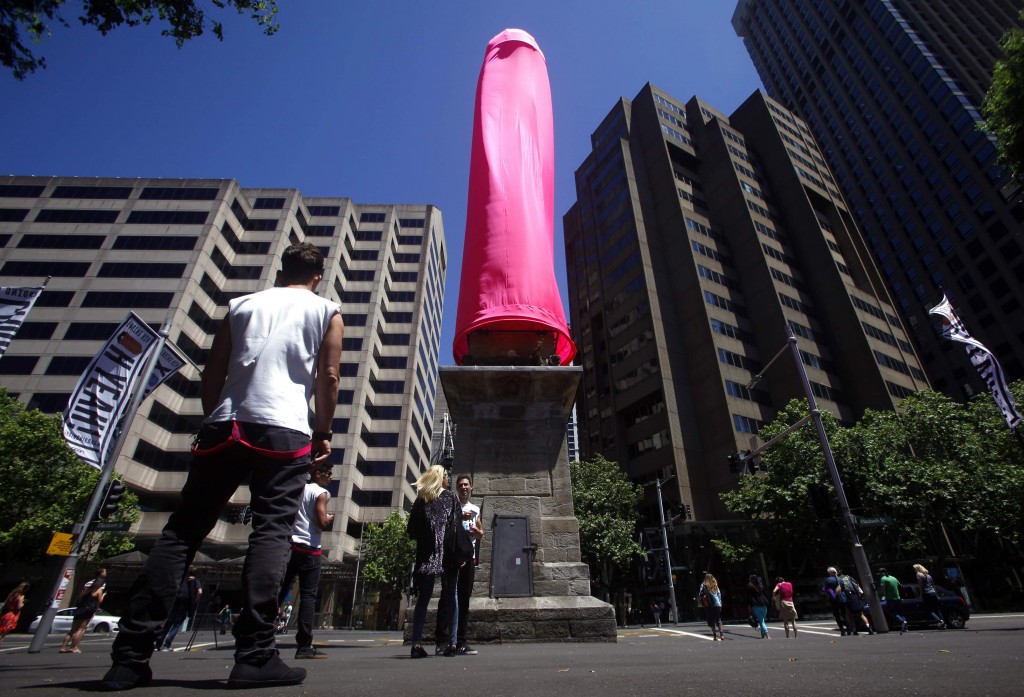 A 'safe sex ambassador' stands underneath an 18-metre pink condom covering the Obelisk situated in Sydney's Hyde Park