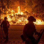 Firefighters battling the King Fire watch as a backfire burns along Highway 50 in Fresh Pond