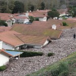 A TV news crew files a report behind damaged homes after a mud slide in Camarillo Springs, California