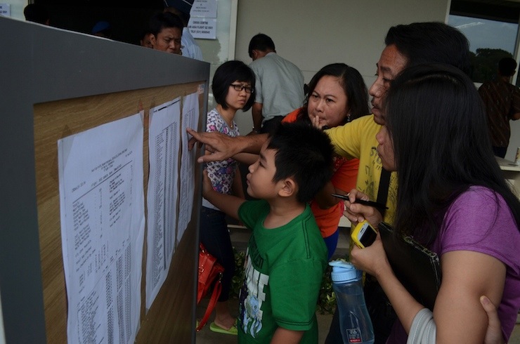 Family members of passengers on board AirAsia flight QZ 8501 look at a passenger list inside a crisis centre at Juanda Airport in Surabaya, East Java