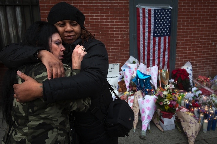 Donna Salvaggio and a woman who gave her name as Reverend Jordan hug at a makeshift memorial at the site where two police officers were shot in the head in the Brooklyn borough of New York