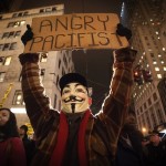 A demonstrator wearing a Guy Fawkes mask walks up 6th Ave as he protests against the police in Manhattan