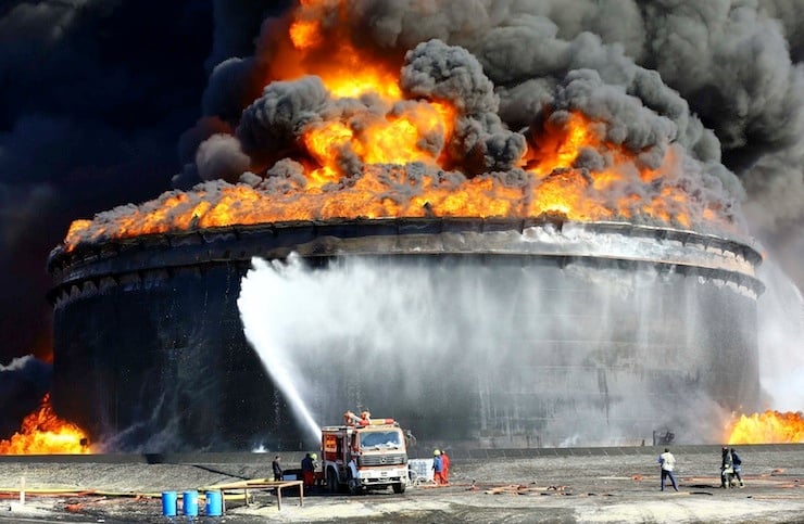 Firefighters work to put out the fire of a storage oil tank at the port of Es Sider in Ras Lanuf