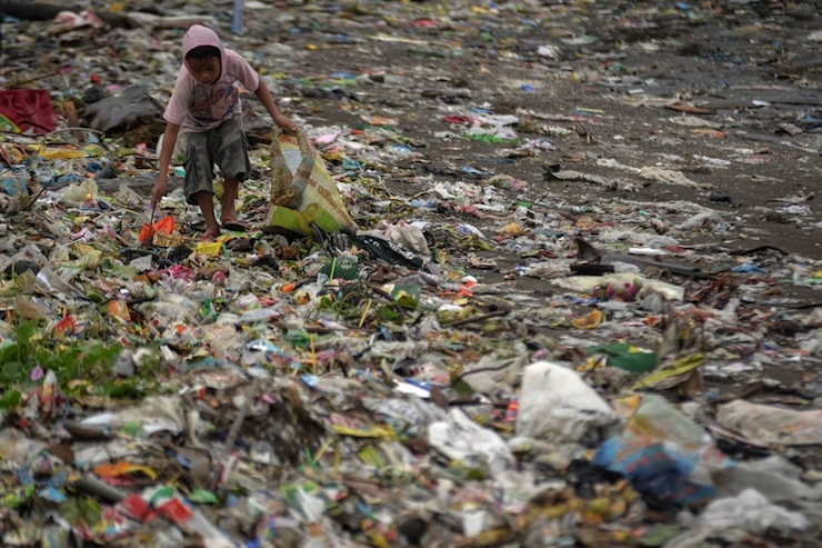 A boy looks for recyclable materials among the garbage washed ashore due to Typhoon Hagupit in Cavite, south of Manila