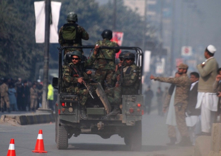 Pakistani security forces drive on a road leading to the Army Public School that is under attack by Taliban gunmen in Peshawar