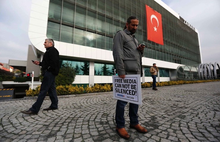 Zaman media group journalist holds banner as he stands outside headquarters of Zaman daily newspaper in Istanbul