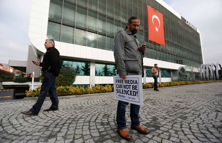 Zaman media group journalist holds banner as he stands outside headquarters of  Zaman daily newspaper in Istanbul