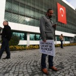 Zaman media group journalist holds banner as he stands outside headquarters of  Zaman daily newspaper in Istanbul