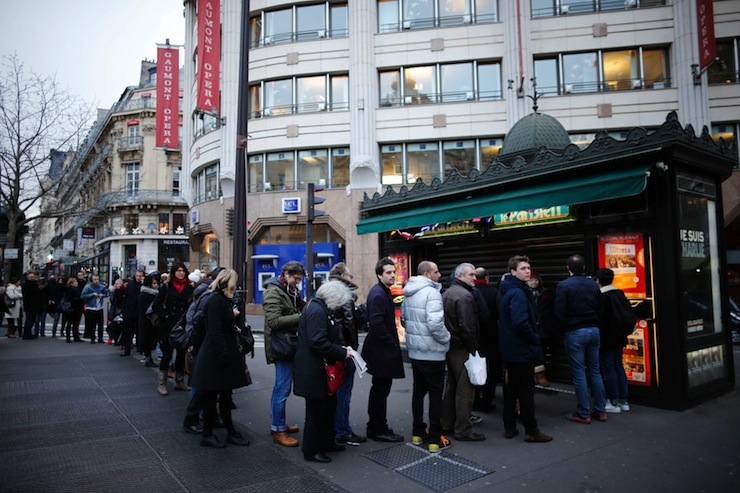 People queue to get a copy of satirical French magazine Charlie Hebdo new issue showing a caricature of Prophet Mohammad in front of a kiosk in Paris