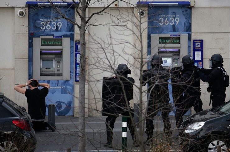A suspect in a hostage taking situation is detained by members of special French RAID forces outside the post offices in Colombes outside Paris