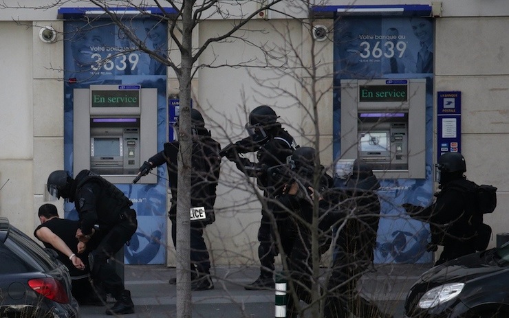 A suspect in a hostage taking situation is detained by members of special French RAID forces outside the post offices in Colombes outside Paris