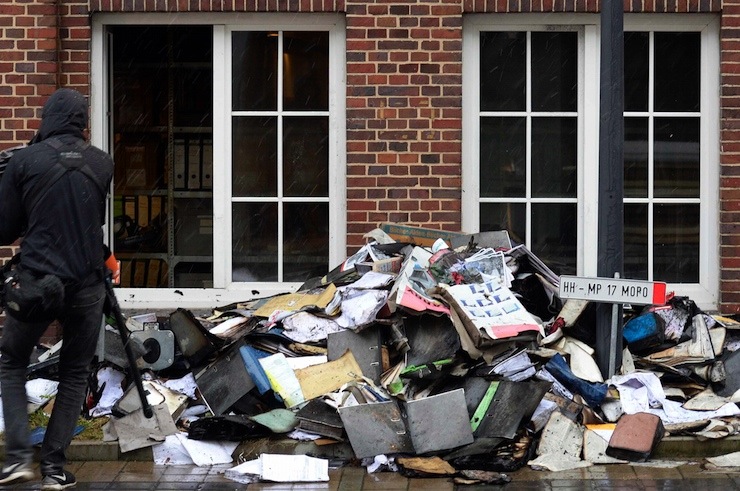 Member of a television crew is seen beside burned files and documents in front of a building of German newspaper Hamburger Morgenpost in Hamburg