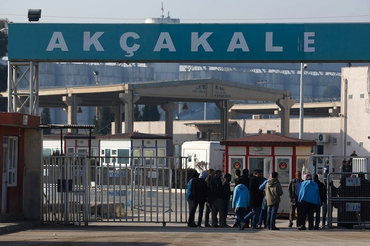 People wait at the Akcakale border gate in Sanliurfa province, southeastern Turkey