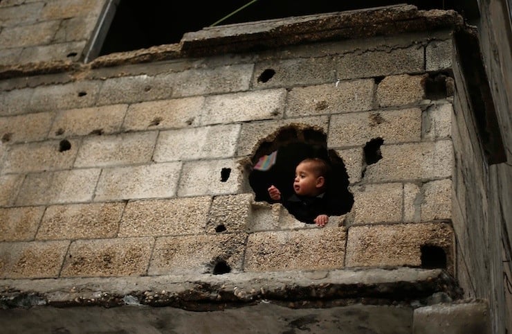 Palestinian boy looks out through a hole in his family house, that witnesses said was damaged by Israeli shelling during the July-August war between Israel and Hamas-led Gaza militants, in the east of Gaza City