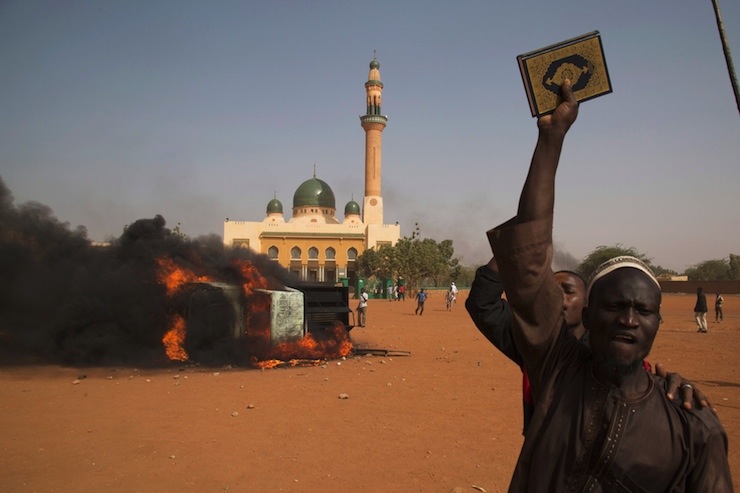 A man holds a copy of the Koran during a protest against Niger President Issoufou's attendance last week at a Paris rally in support of French satirical weekly Charlie Hebdo, in Niamey