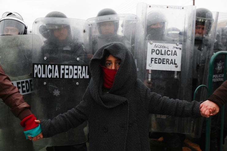 Child holds hands with demonstrators while standing in front of federal policemen during a protest against the visit of Mexico's President Enrique Pena Nieto to the city, in Ciudad Juarez