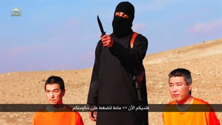 A masked person holding a knife speaks as he stands in between two kneeling men in this still image taken from an online video released by the militant Islamic State group