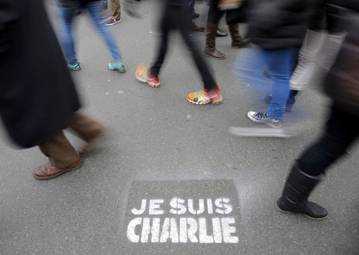 People walk past a grafitti tag reading "I am Charlie" as they take part in a solidarity march (Marche Republicaine) in the streets of Paris