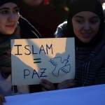 Two young women hold a placard that reads “Islam = Peace” during a rally by members of the Muslim community of Madrid outside Madrid's Atocha train station