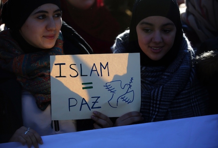 Two young women hold a placard that reads "Islam = Peace" during a rally by members of the Muslim community of Madrid outside Madrid's Atocha train station