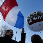 People hold a balloon and a French flag as they attend the solidarity march in the streets of Paris