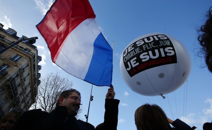 People hold a balloon and a French flag as they attend the solidarity march in the streets of Paris