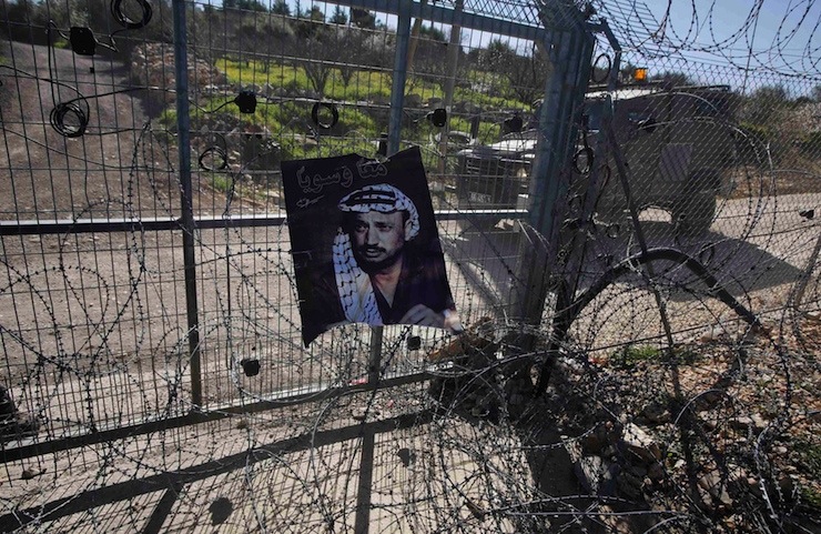 A poster depicting late Palestinian leader Yasser Arafat hangs on a settlement gate during a protest by Palestinians against Jewish settlements, in Biet Ommar