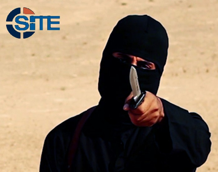 A masked, black-clad militant brandishes a knife in this still image from video