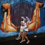 Revellers walk past a graffiti as they arrive at the annual carnival block party known as “Casas comigo” or “Marry me” in Sao Paulo