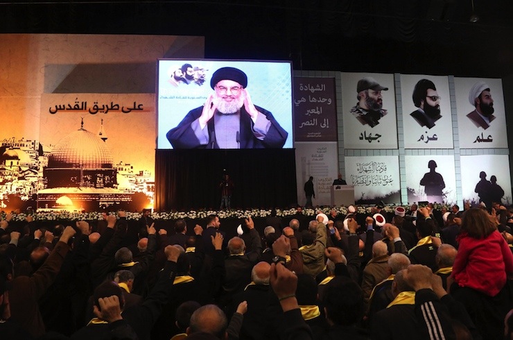 Lebanon's Hezbollah leader Hassan Nasrallah greets his supporters through a giant screen during a rally commemorating the annual Hezbollah Martyrs' Leader Day in Beirut's southern suburbs