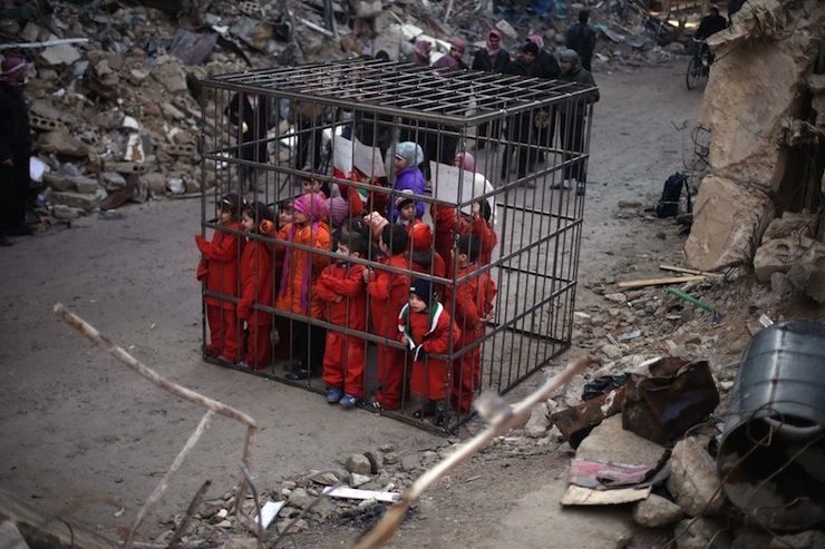 Children carry banners inside a cage during a protest, against forces loyal to Syria's President Bashar al-Assad, in Douma Eastern Al-Ghouta, near Damascus
